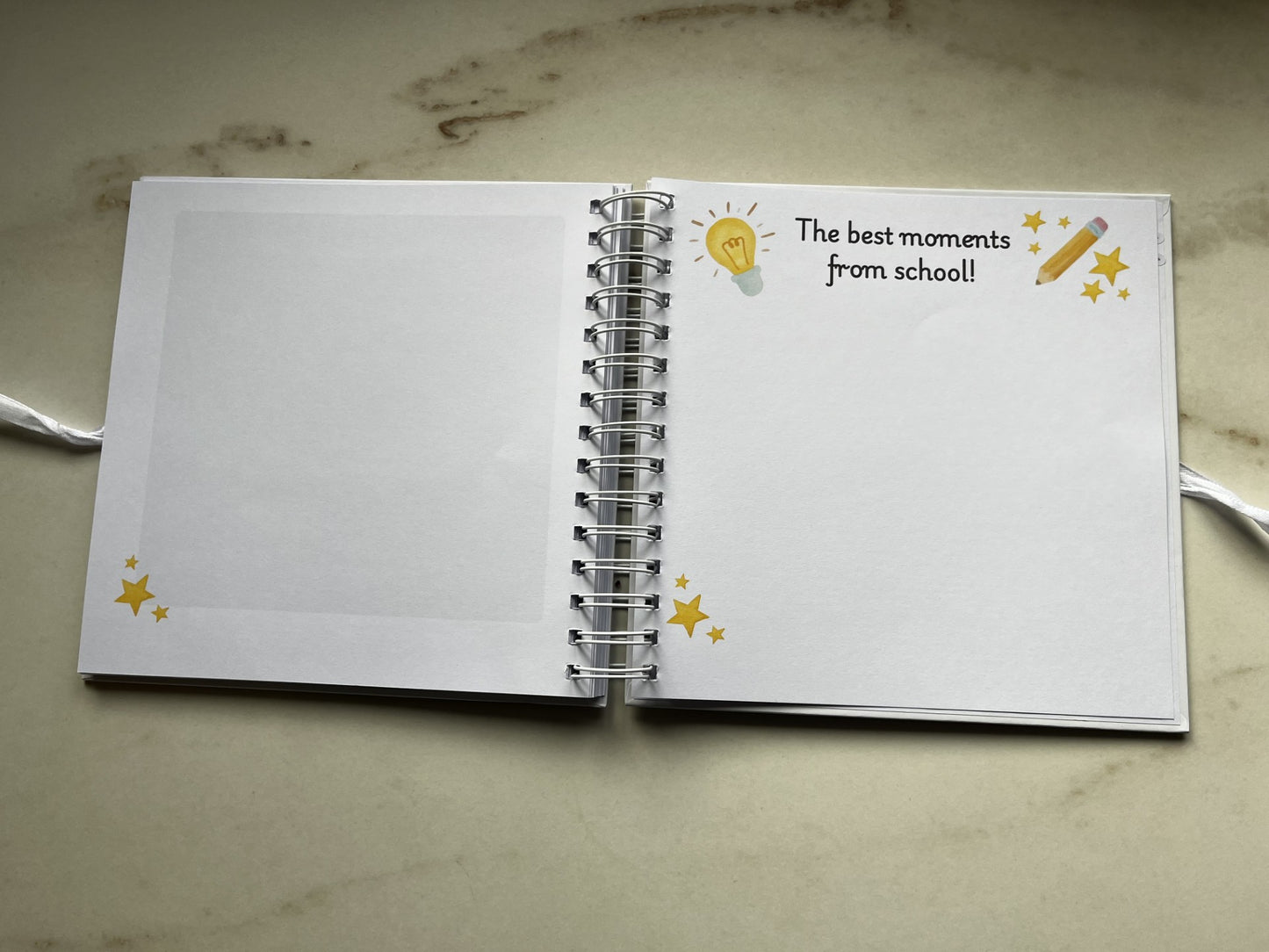 Open notebook with decorative cover on a marble surface. The best moments of school. Note memories from primary school