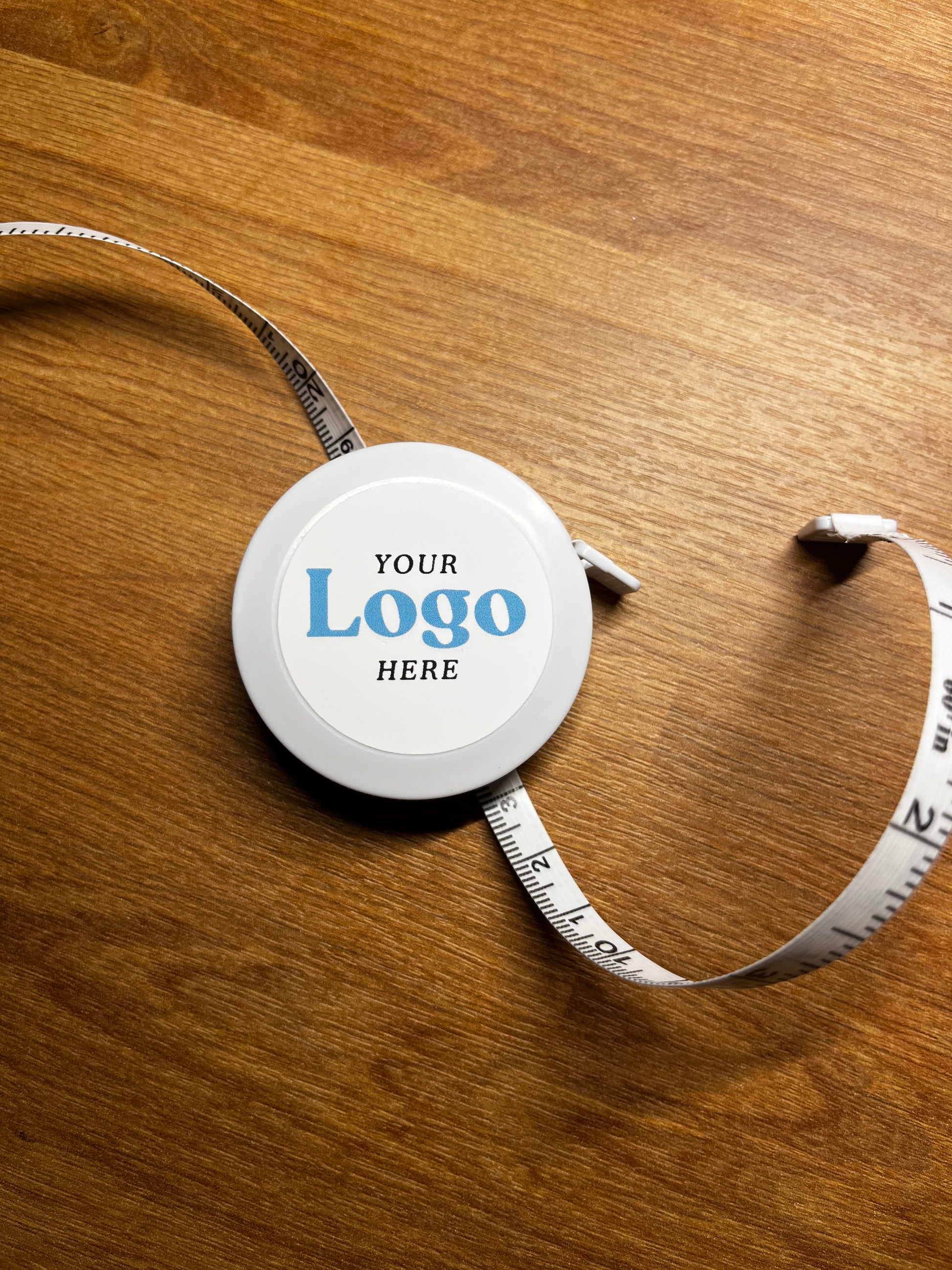 Measuring tape with a customizable logo on a wooden surface
