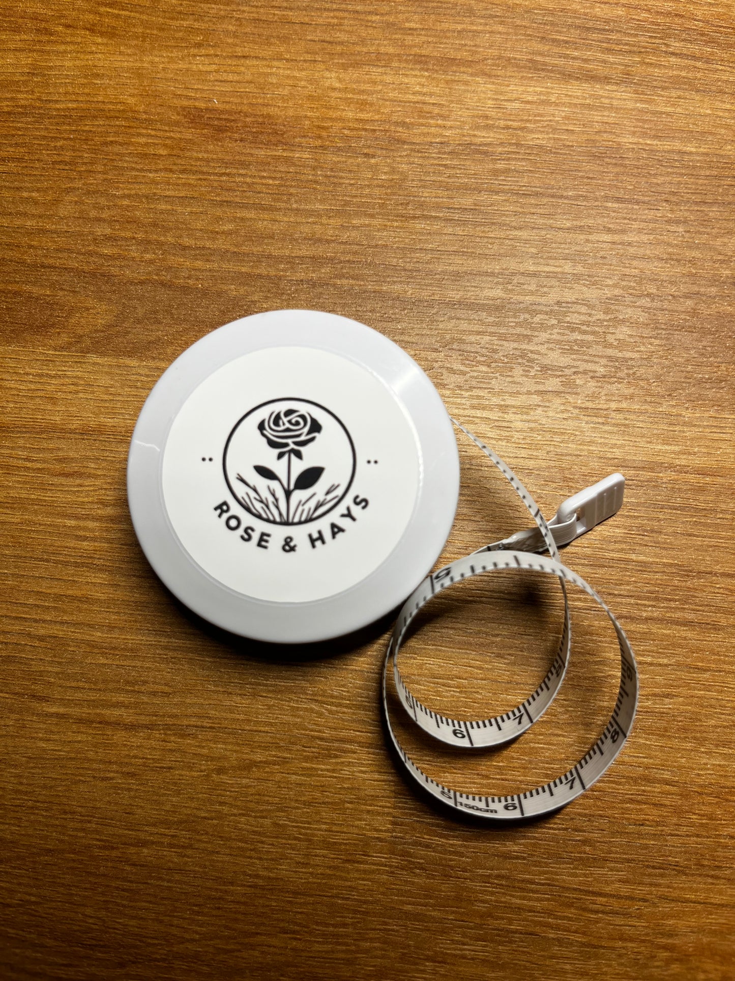 White tape measures with a black logo on a wooden surface