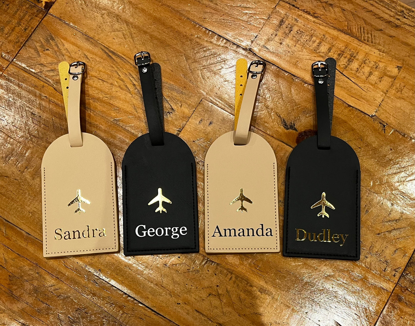 Four personalized luggage tags with names on a wooden surface