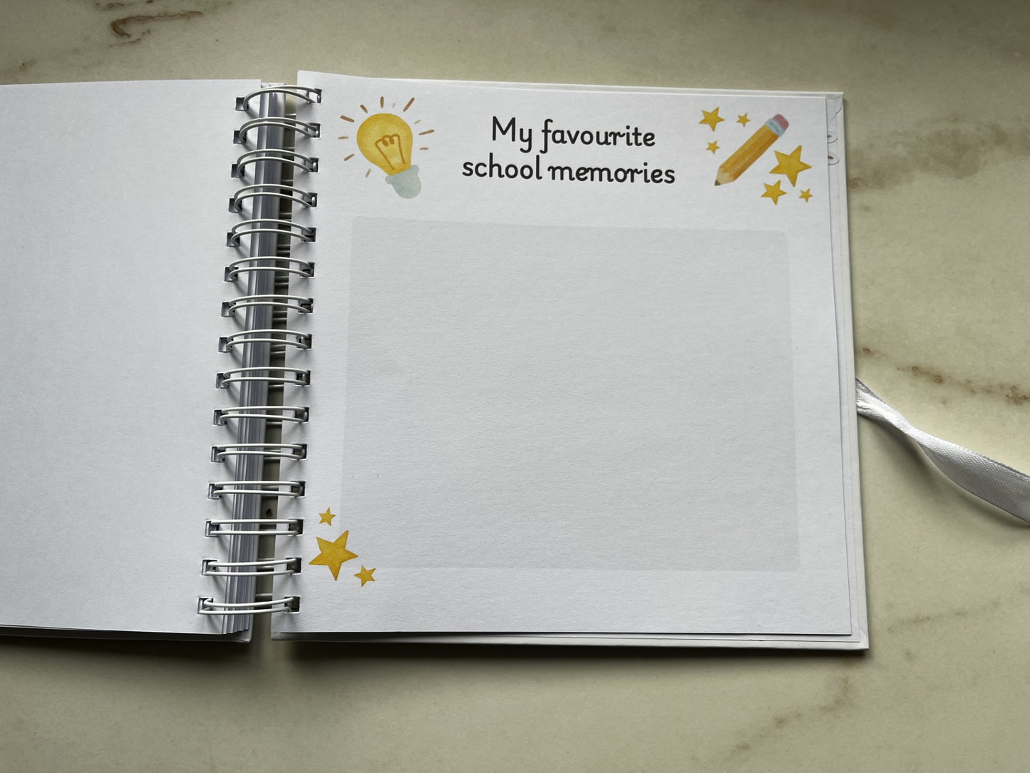 Open notebook with a page titled 'My favourite school memories' on a marble surface. Last day of primary school