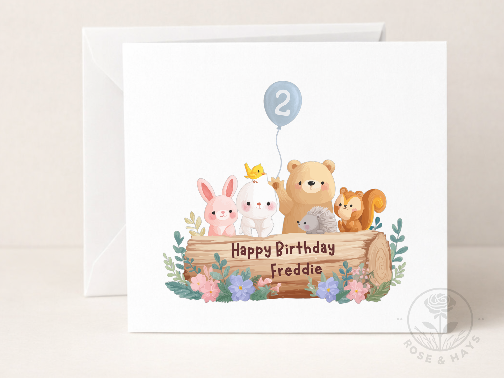 Birthday card with cartoon animals around a log, featuring the number 2 and flowers on a white background.